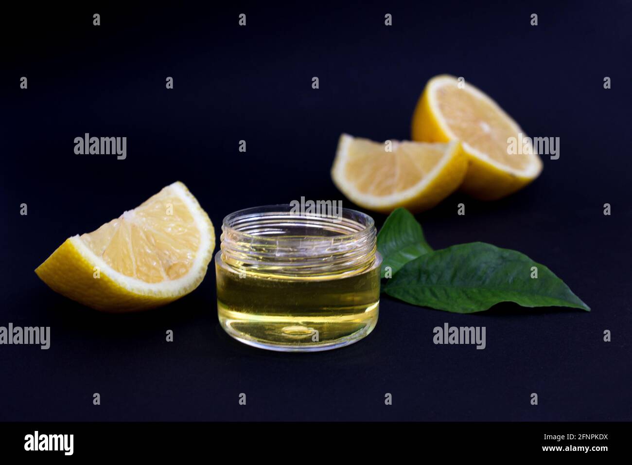 Fette di limone e olio cosmetico di limone su fondo nero. Primo piano Foto Stock