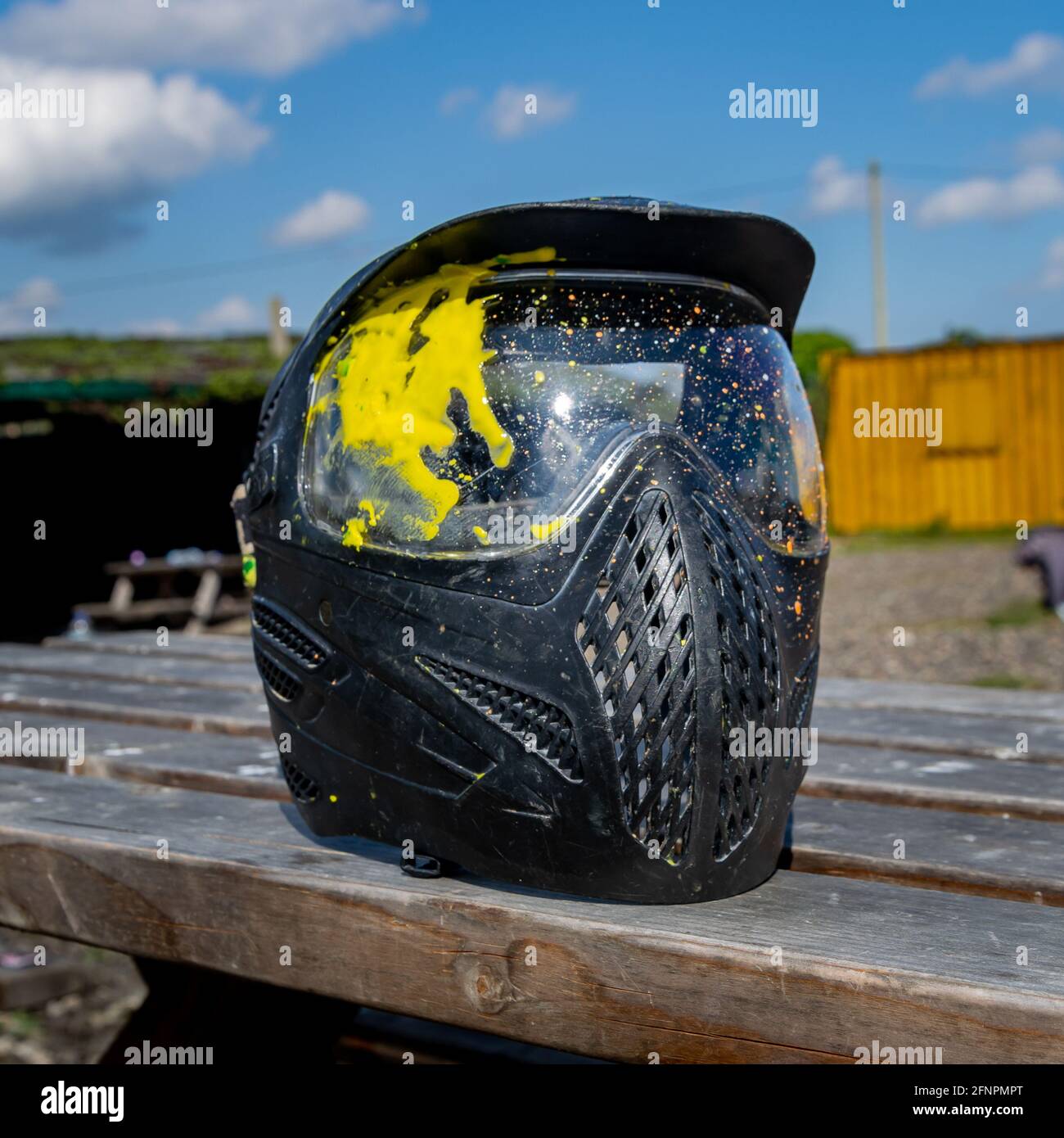 Maschera di sicurezza protettiva per paintball con singolo contrassegno giallo dopo un gioco c'è un cielo blu con nuvole dentro lo sfondo Foto Stock