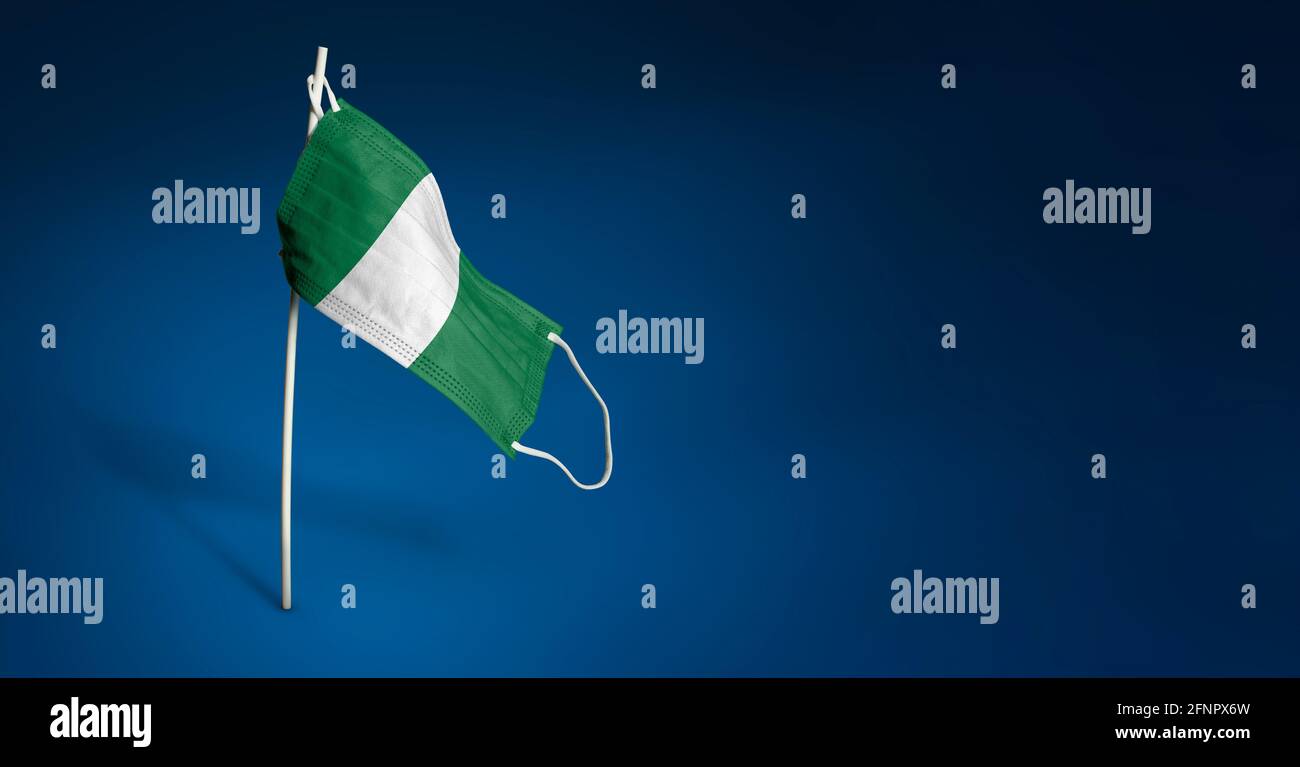 Maschera nigeriana su sfondo blu scuro. Bandiera sventolante della Nigeria dipinta su maschera medica sul palo. Flag di attacco del virus. Concetto del banner della Fight ag Foto Stock