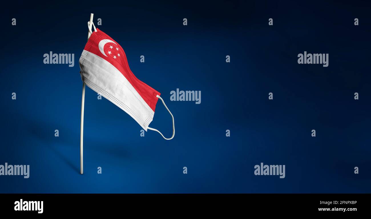 Maschera Singapore su sfondo blu scuro. Bandiera ondulata di Singapore dipinta su maschera medica sul palo. Flag di attacco del virus. Concetto della bandiera della coscia Foto Stock