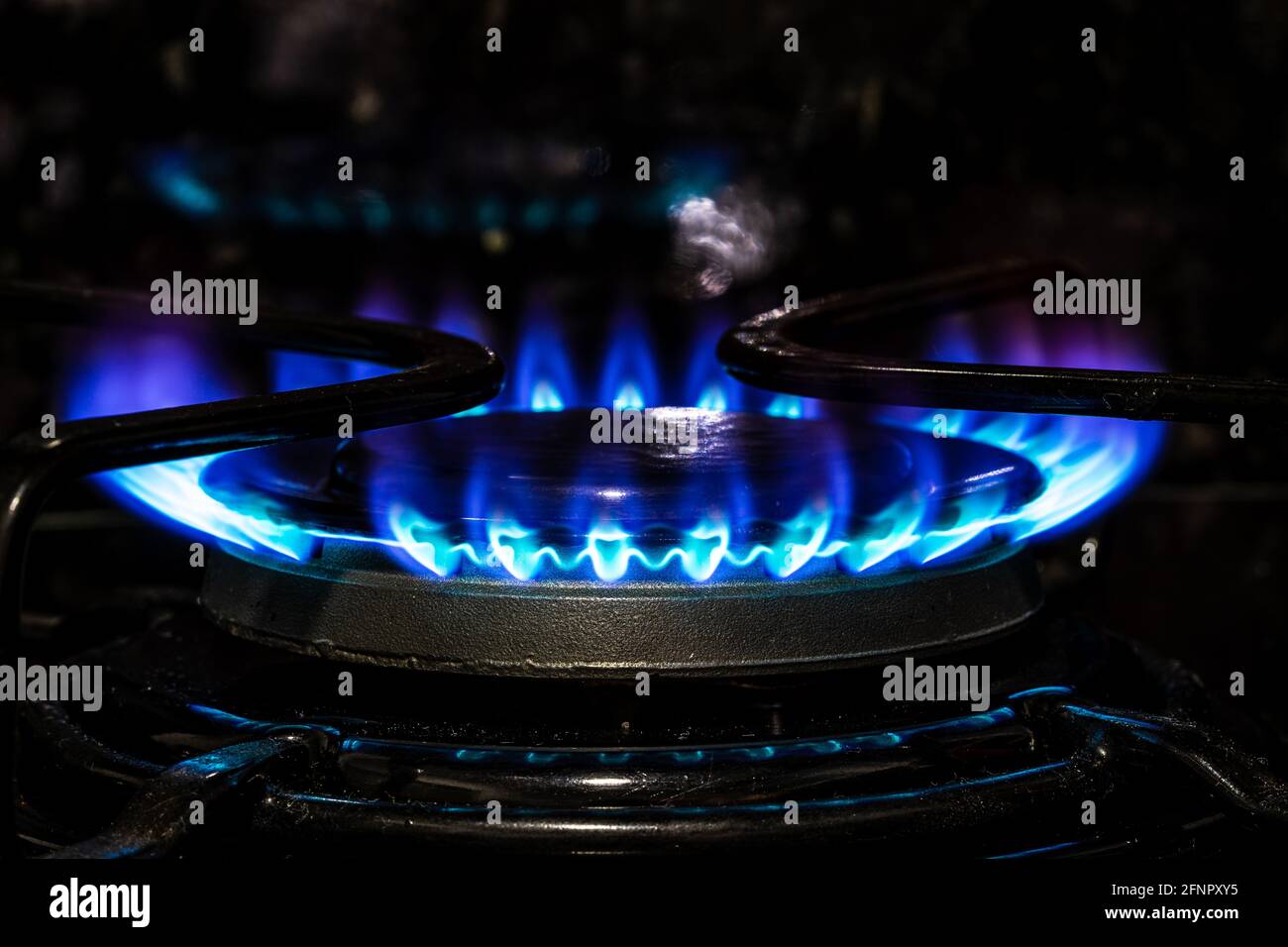 Bruciatore a gas con fiamma blu, anello di fuoco incandescente su stufa da cucina. Foto Stock