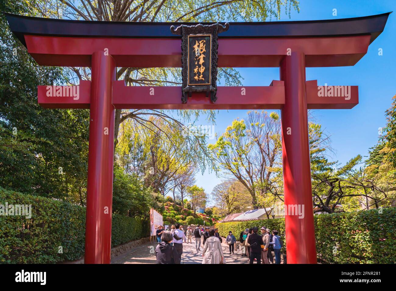 tokyo, giappone - aprile 16 2020: Grande portale vermiglio Torii all'ingresso del santuario giapponese Shintoista Nezu con turisti che camminano sul sando pa Foto Stock