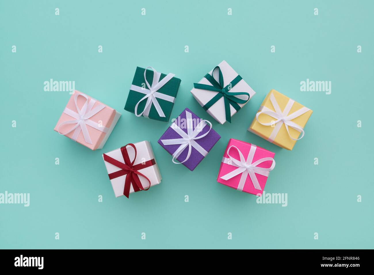Diverse scatole regalo o in bonbon con nastri su sfondo verde pastello. Vista dall'alto, disposizione piatta. Foto Stock