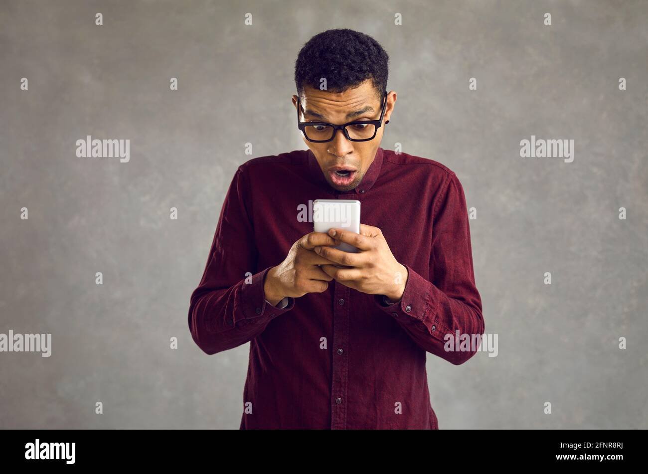 Sorpreso afro americano uomo con bocca aperta guardando il telefono screenshot di studio Foto Stock