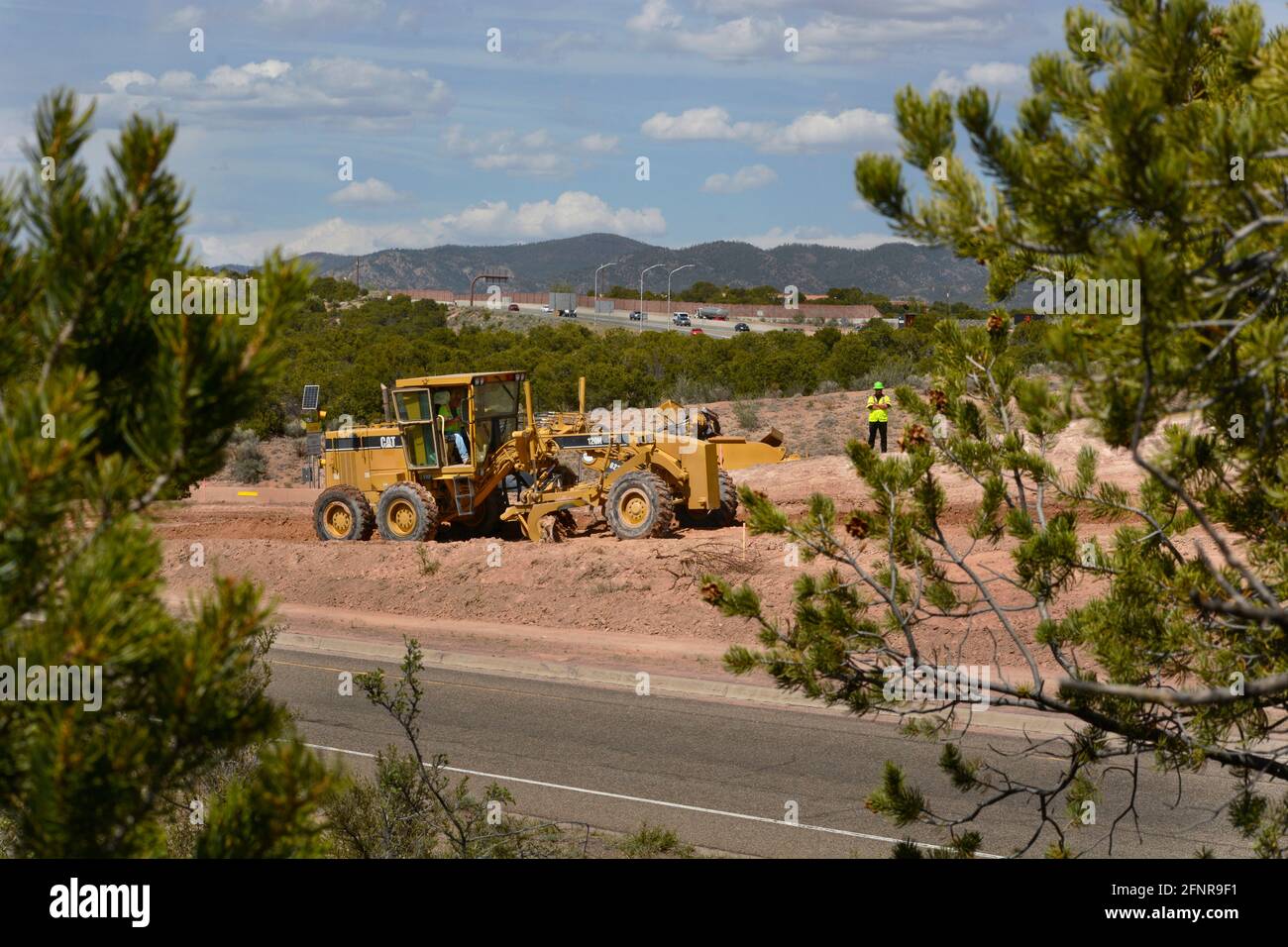 Un operatore di attrezzature pesanti utilizza un motorgrader Caterpillar 120H per movimentare lo sporco in un cantiere di costruzione di strade a Santa Fe, New Mexico. Foto Stock