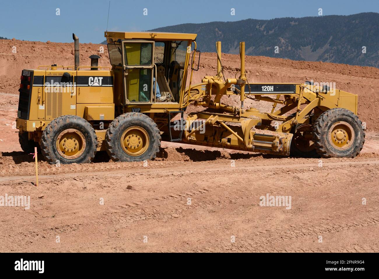 Un operatore di attrezzature pesanti utilizza un motorgrader Caterpillar 120H per movimentare lo sporco in un cantiere di costruzione di strade a Santa Fe, New Mexico. Foto Stock