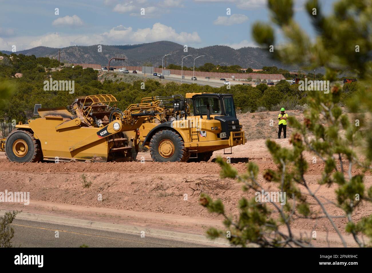 Un operatore di attrezzature pesanti utilizza un raschiatore per trattori gommati Caterpillar 623H per rimuovere lo sporco nel cantiere di miglioramento dell'autostrada a Santa Fe, New Mexico. Foto Stock