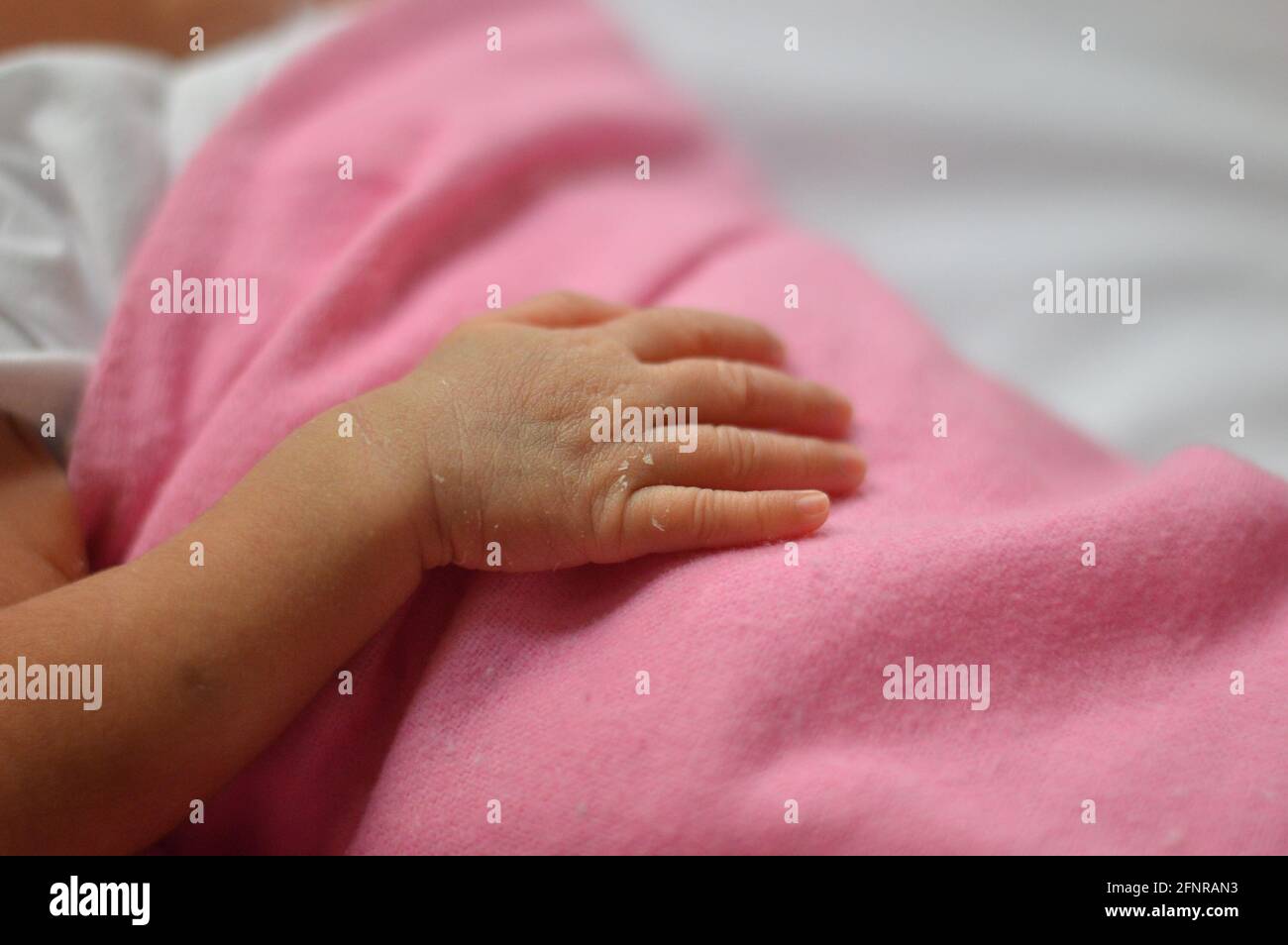 Mano del bambino su una coperta rosa Foto Stock