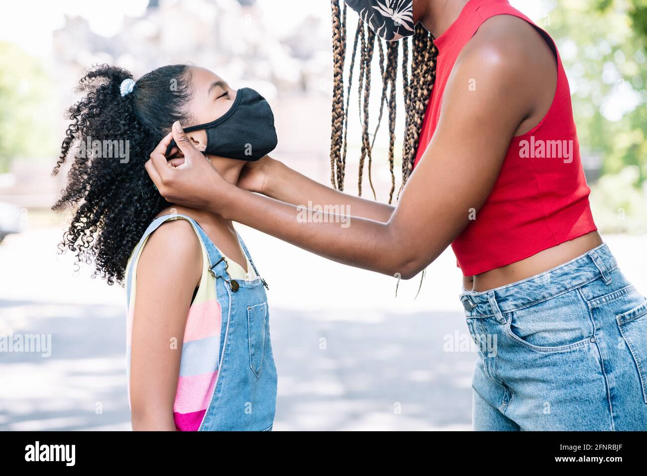 Madre che mette una maschera di faccia su sua figlia. Foto Stock