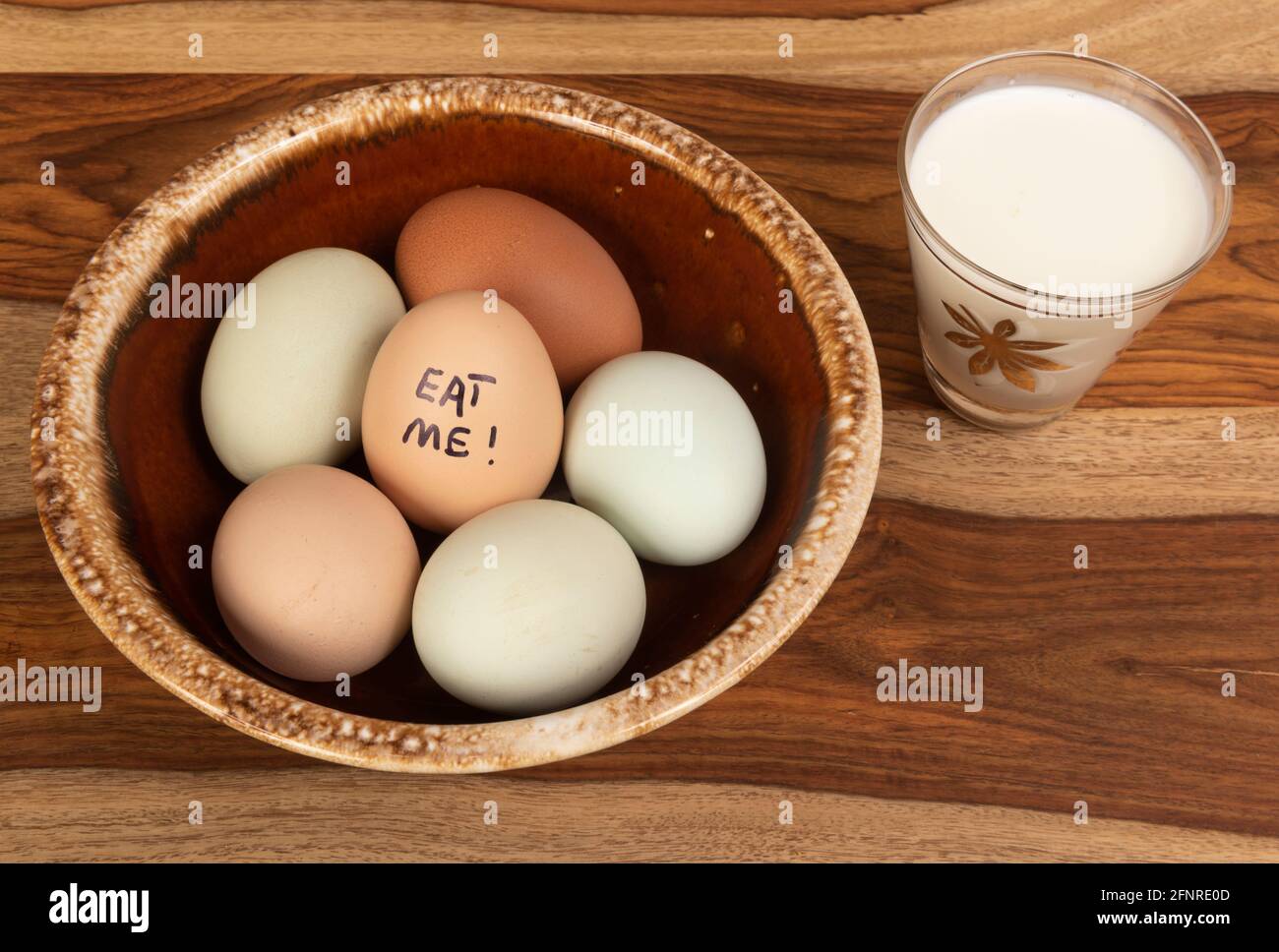 Una ciotola marrone di uova con un piccolo bicchiere di latte. Una frase  umorosa è scritta su una delle uova Foto stock - Alamy