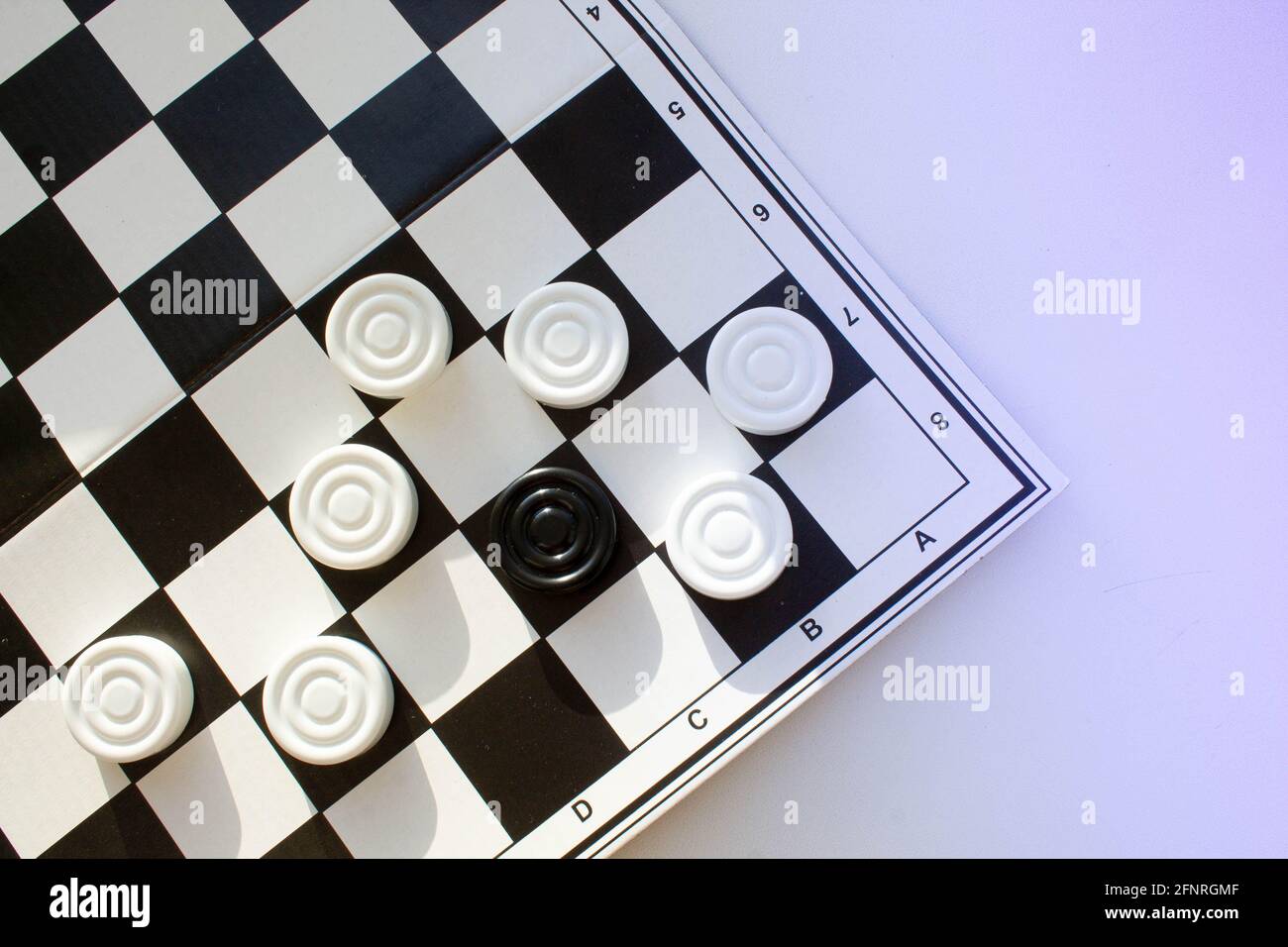 Gioco da tavolo di dama. Chip bianchi e neri per il gioco. Campo di Scacchi. Le pedine si spostano in primo piano. Checker in mano. Foto Stock