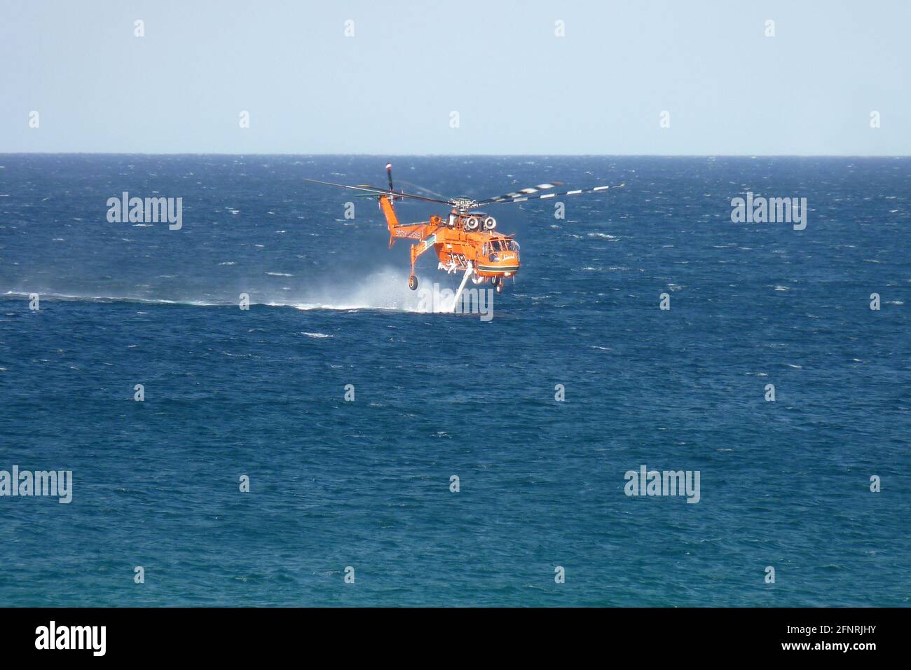 Erickson S64E Airgrane solleva l'acqua di mare attraverso il suo tubo per lo snorkeling, per dispiegarsi su un vicino fuoco di fuoco vicino al lago Macquarie, NSW, Australia Foto Stock