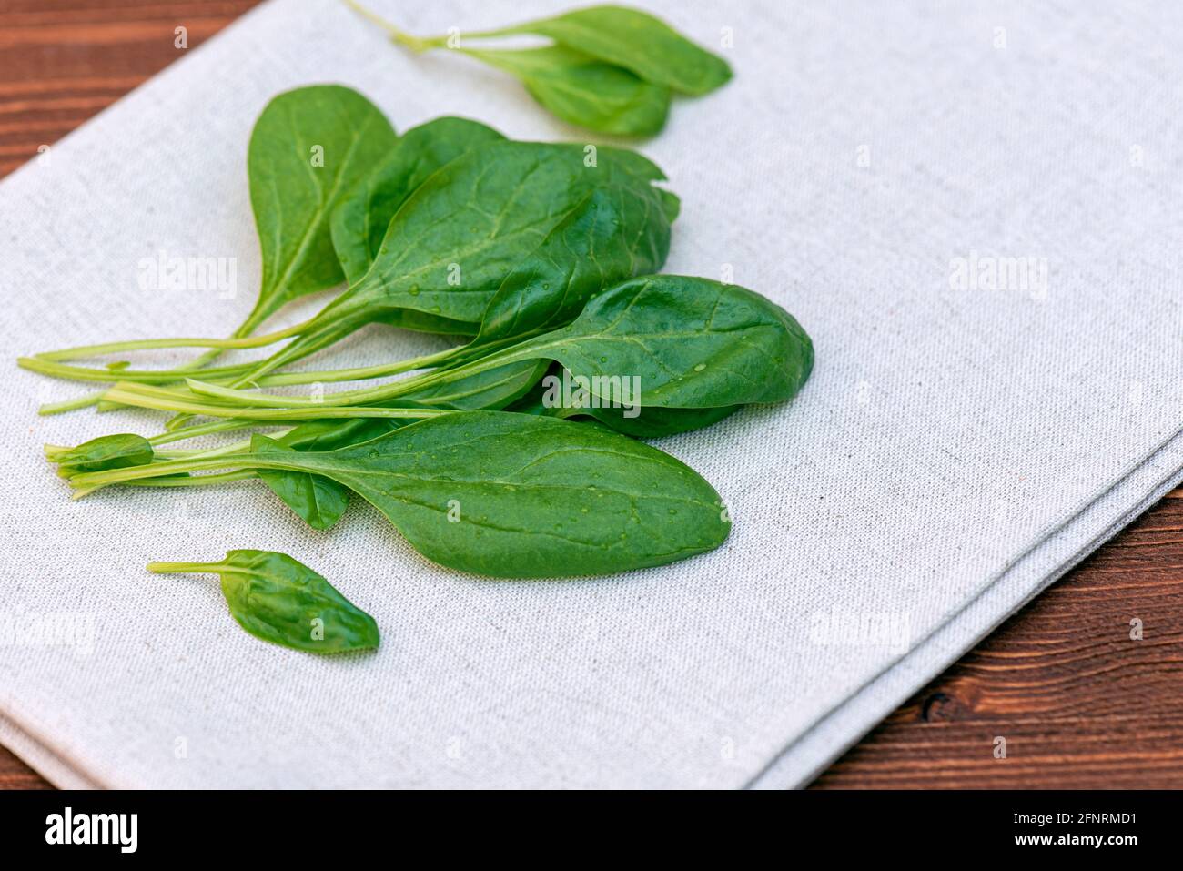 Spinaci verdi freschi e tovaglie su tavolo di legno in cucina, vista dall'alto Foto Stock