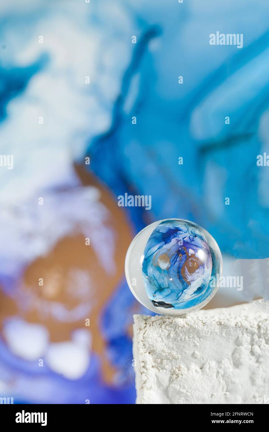 Una palla di vetro trasparente su uno sfondo astratto blu. La tecnica dell'inchiostro alcolico. Spazio di copia. Foto Stock