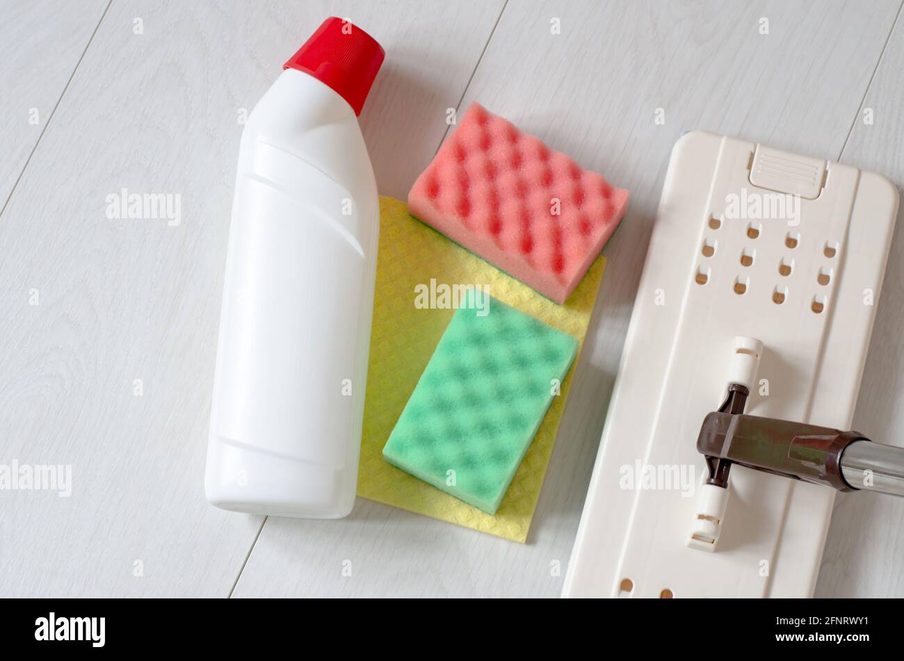 Un mop beige, spugne e una bottiglia di detergente per pavimenti. Prodotti per la pulizia Foto Stock