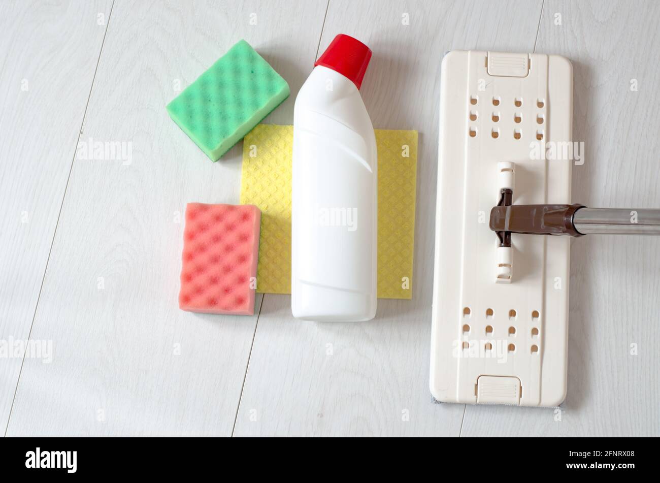 Un mop beige, spugne e una bottiglia di detergente per pavimenti. Prodotti per la pulizia Foto Stock