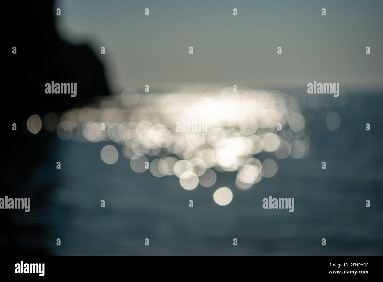 Astratto natura estate oceano tramonto mare sfondo. Piccole onde sulla superficie dell'acqua in movimento sfocano con le luci bokeh dall'alba. Vacanza, vacanza e. Foto Stock