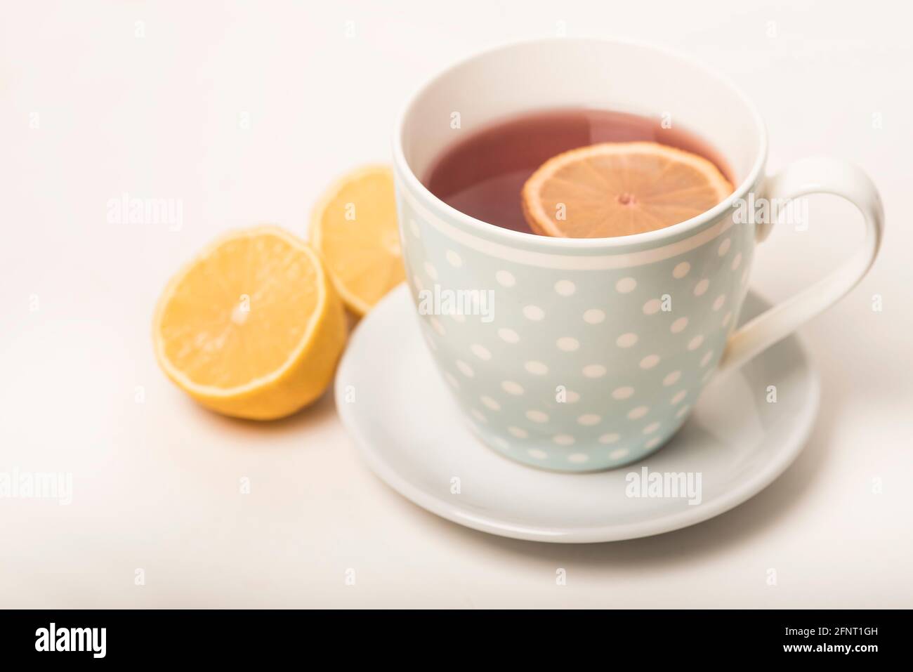 Una tazza di tè al limone su un piatto e sfondo bianco con due metà di un  limone Foto stock - Alamy