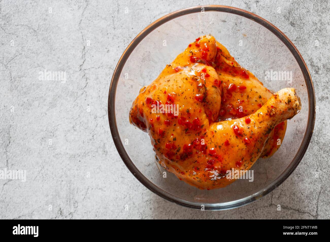 Pollo con salsa piri o peri marinata in un recipiente di vetro. Su sfondo concreto Foto Stock