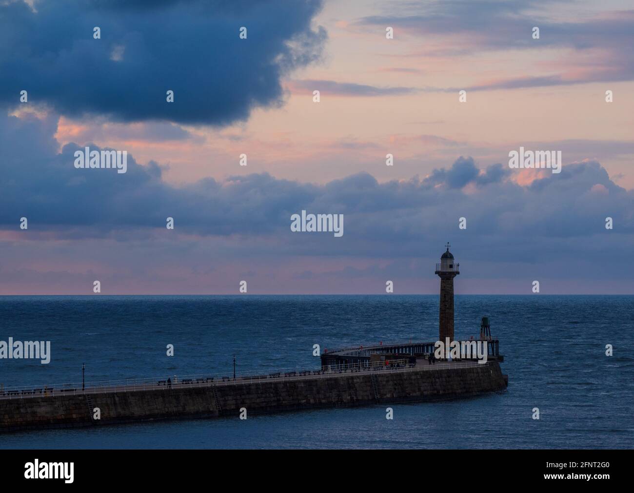 Faro di Whitby Harbour al tramonto con un cielo rosa al tramonto. Foto Stock