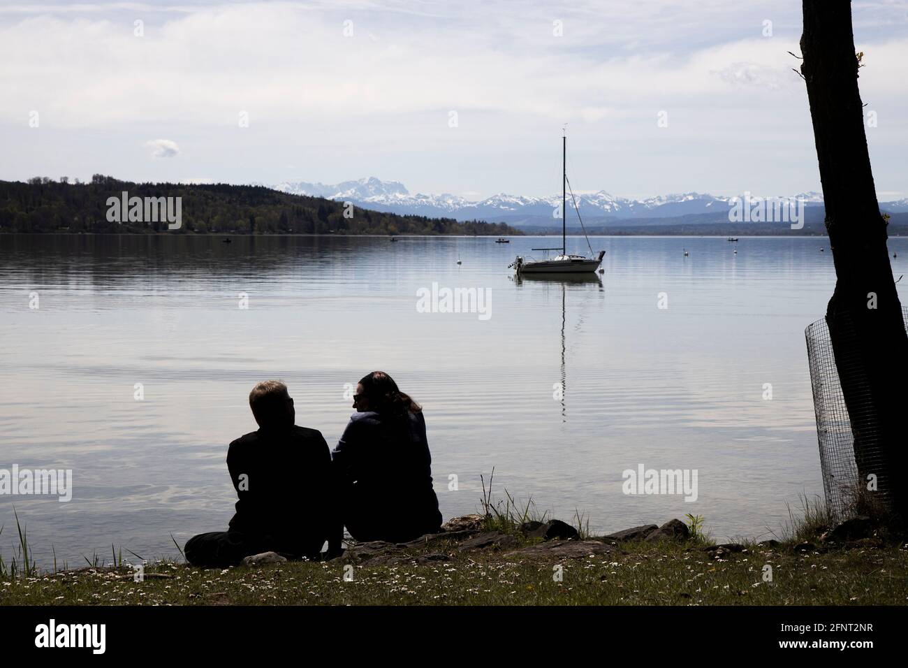 Coppia seduta sulla riva del lago Ammer a Herrsching, alta Baviera, Germania, Europa. Foto Stock