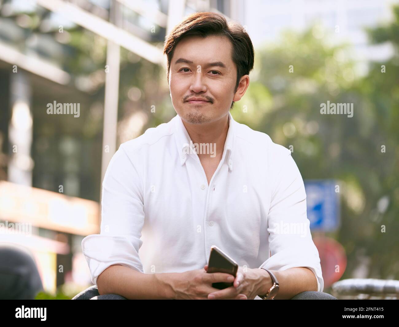 ritratto all'aperto di un uomo d'affari asiatico di successo che guarda la fotocamera sorridente Foto Stock