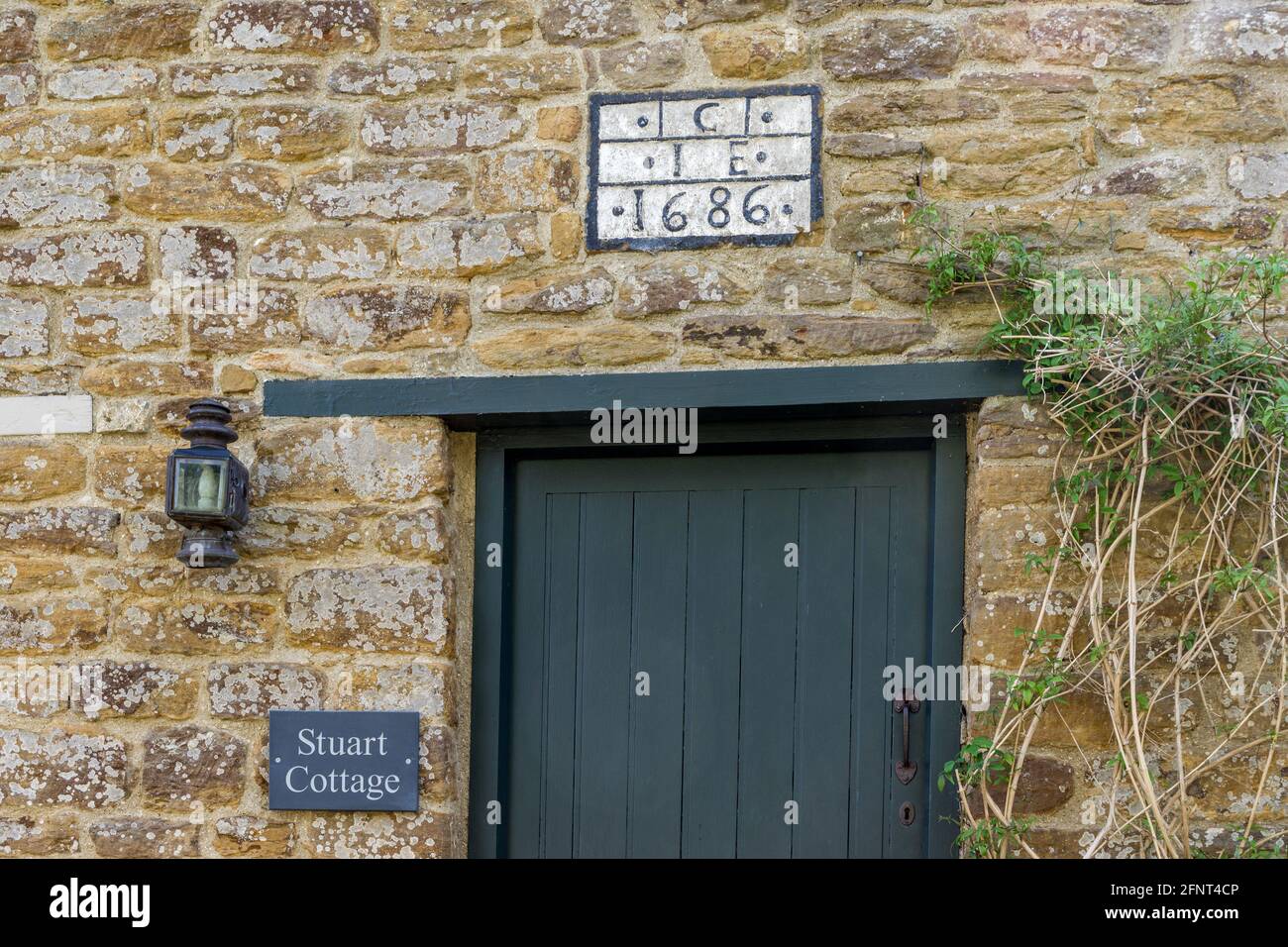 Frontage di Stuart Cottage nel villaggio di Badby, Northamptonshire, UK; targa sopra la porta notando che risale al 1686 Foto Stock