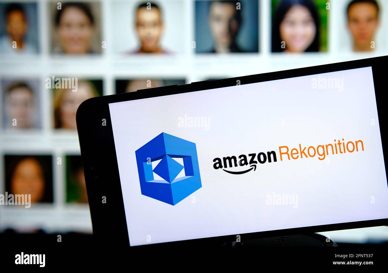 Amazon Rekognition logo della piattaforma AWS sullo smartphone e volti sfocati sul retro. Concetto per software di riconoscimento dei volti basato su cloud. Nessuna modifica nel post. Foto Stock