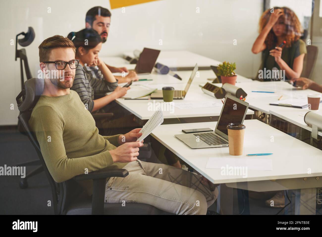Calmo lavoratore di ufficio maschile che posa sul suo posto di lavoro Foto Stock
