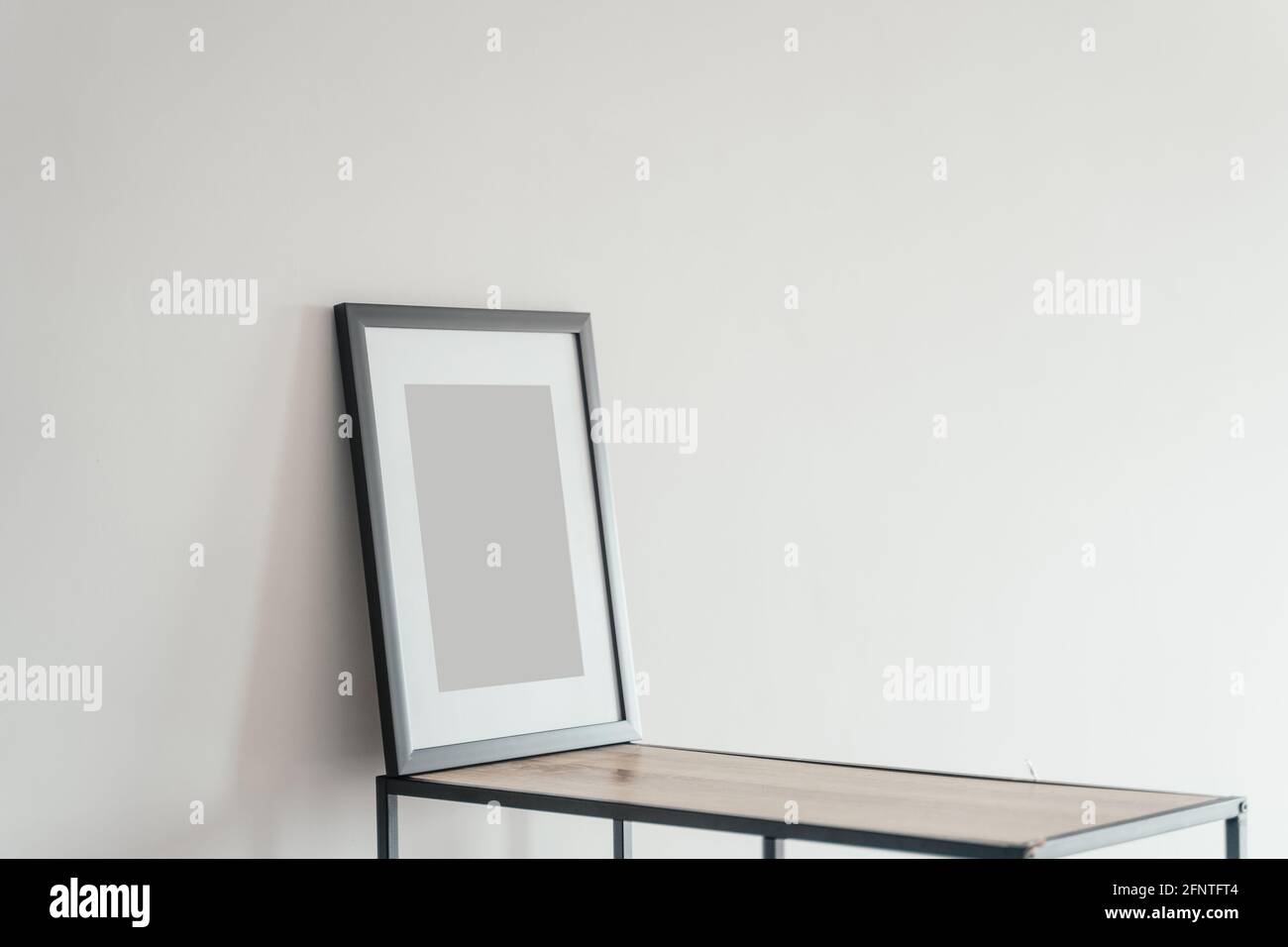 La cornice fotografica in legno bianco si trova all'interno su uno sfondo bianco. Cornice poster mockup. Foto Stock
