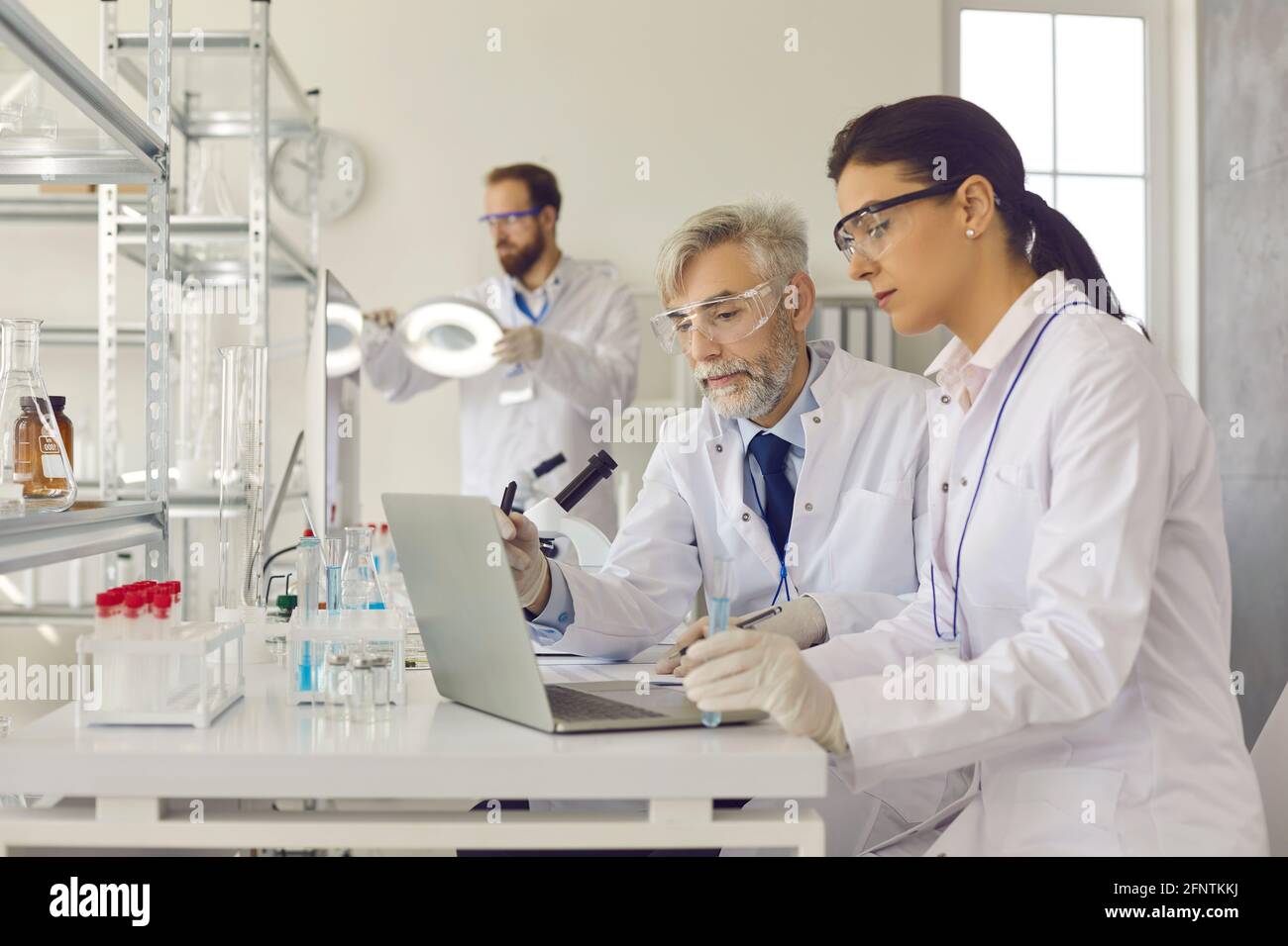 Scienziati anziani e giovani che utilizzano un computer portatile mentre si svolgono attività mediche ricerca insieme Foto Stock