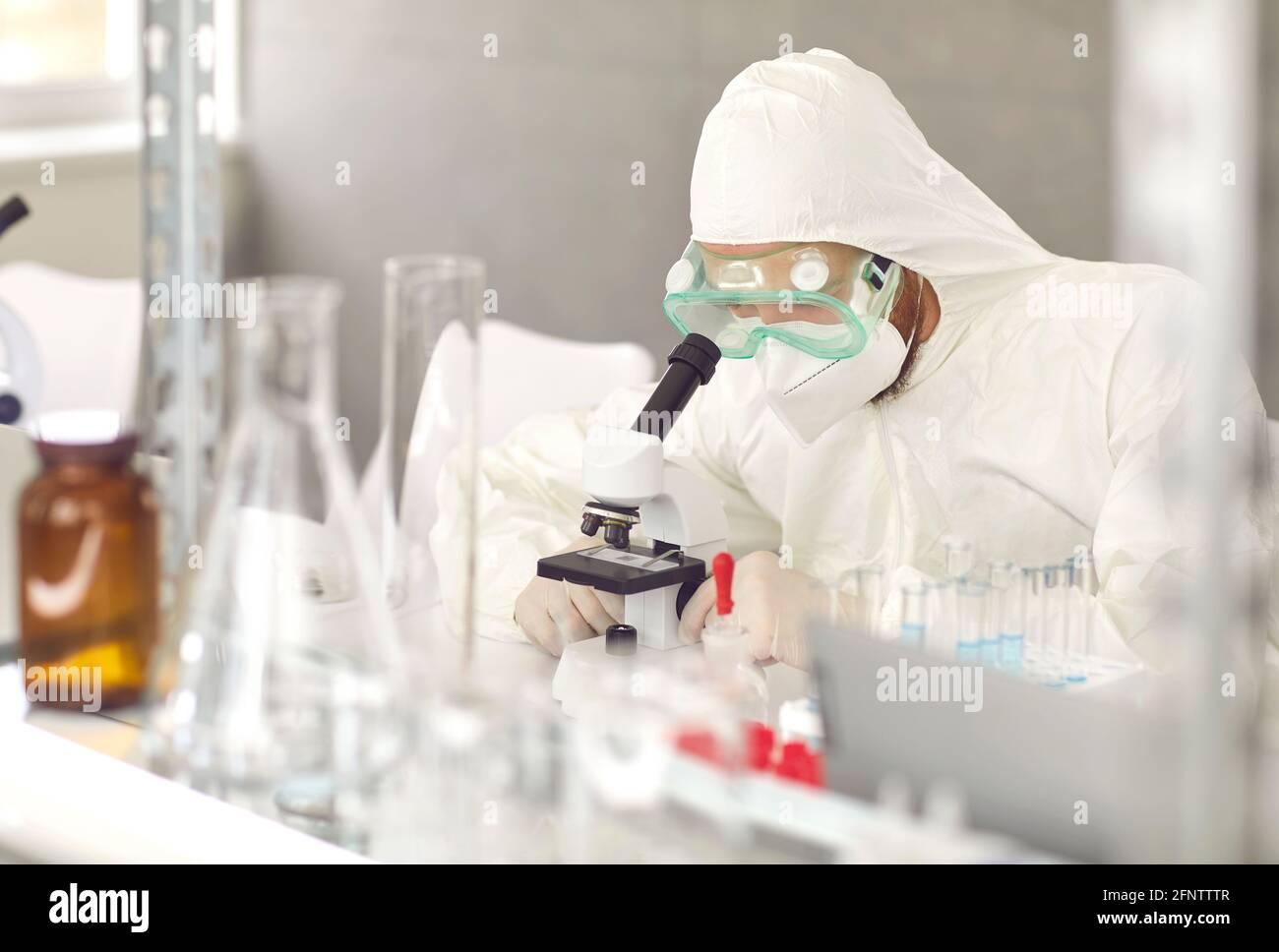 Scienziato che lavora con il microscopio da laboratorio, facendo ricerche e sviluppando nuovi trattamenti efficaci Foto Stock