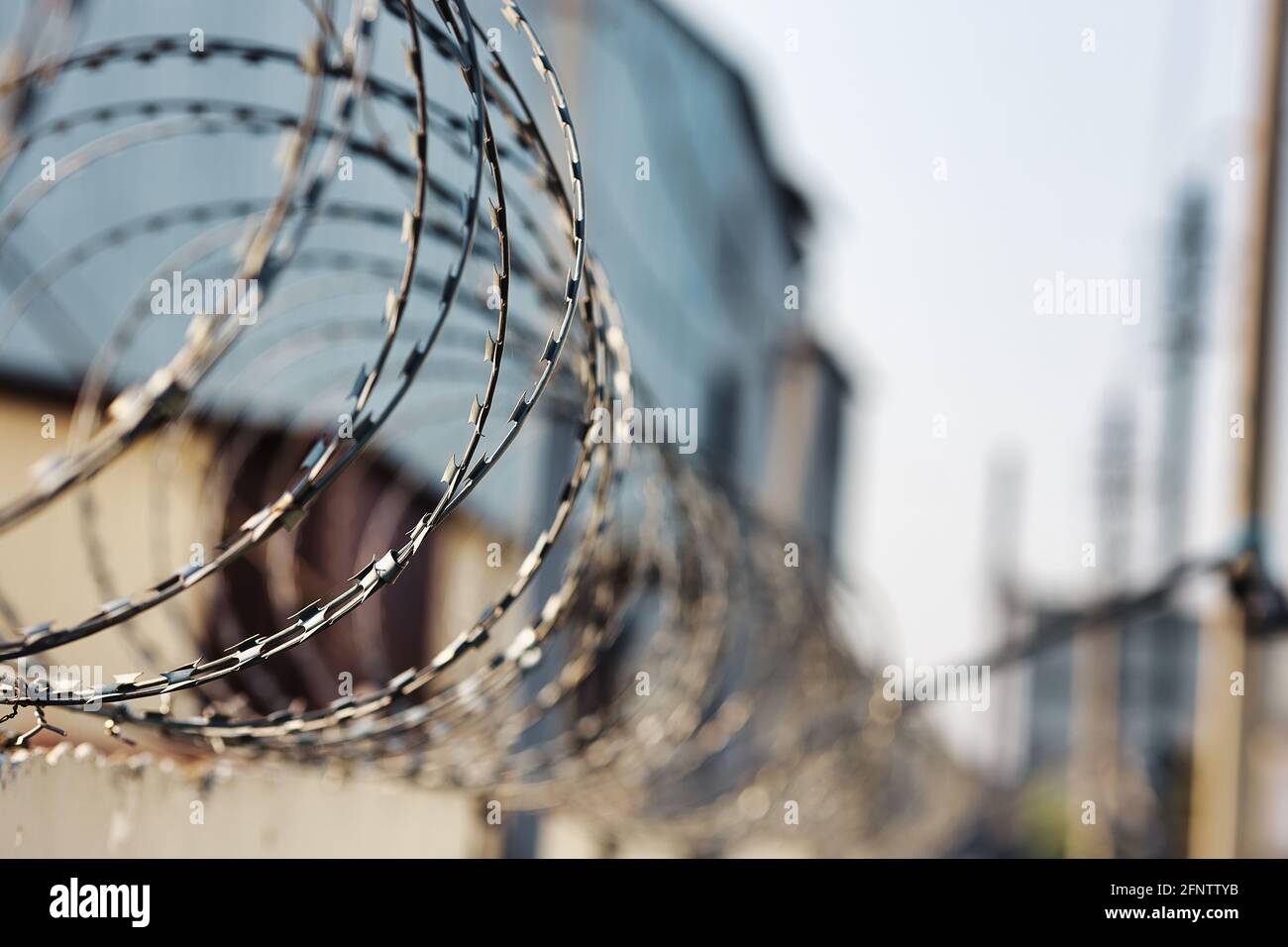 Spirali di filo spinato su una recinzione di cemento. Un simbolo di incarcerazione e di mancanza di libertà. Punizione per un crimine. Foto Stock