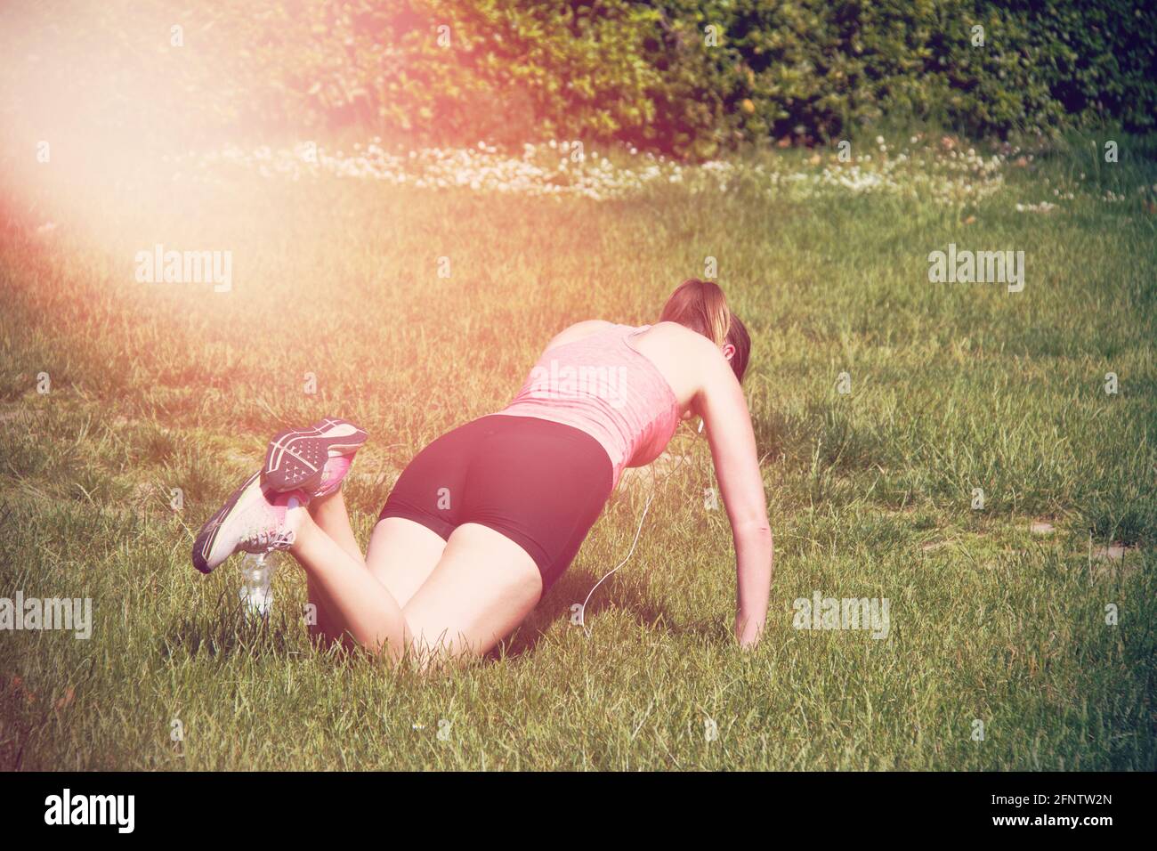 Vista posteriore di una ragazza sportiva, mentre sta facendo push-up sulle  ginocchia per riscaldare i muscoli pettorali, triceps e spalle . Donna che  pratica esercizi Foto stock - Alamy
