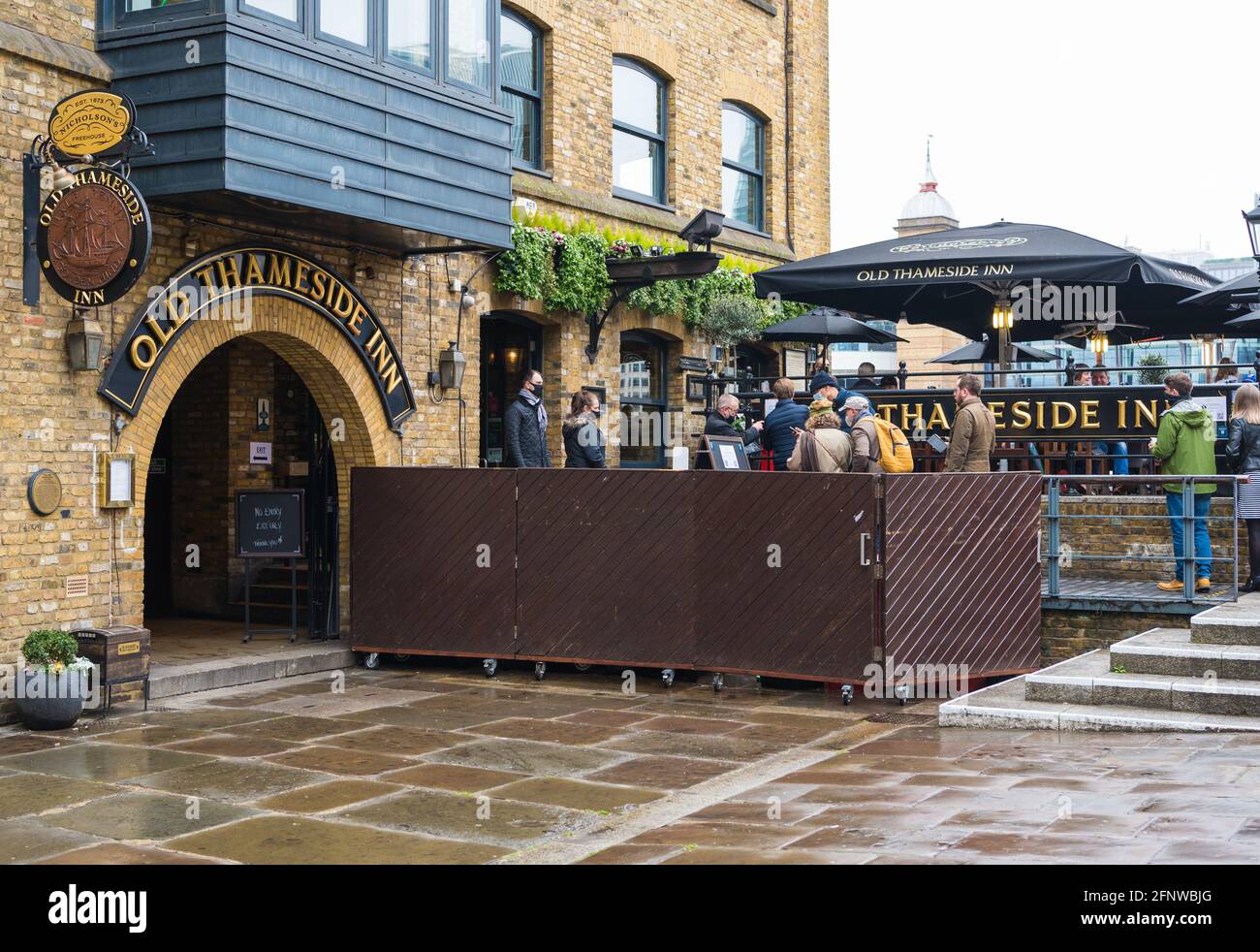 Persone che aspettano un tavolo esterno all'Old Thameside Inn, Pickfords Wharf, Londra, Inghilterra, Regno Unito Foto Stock