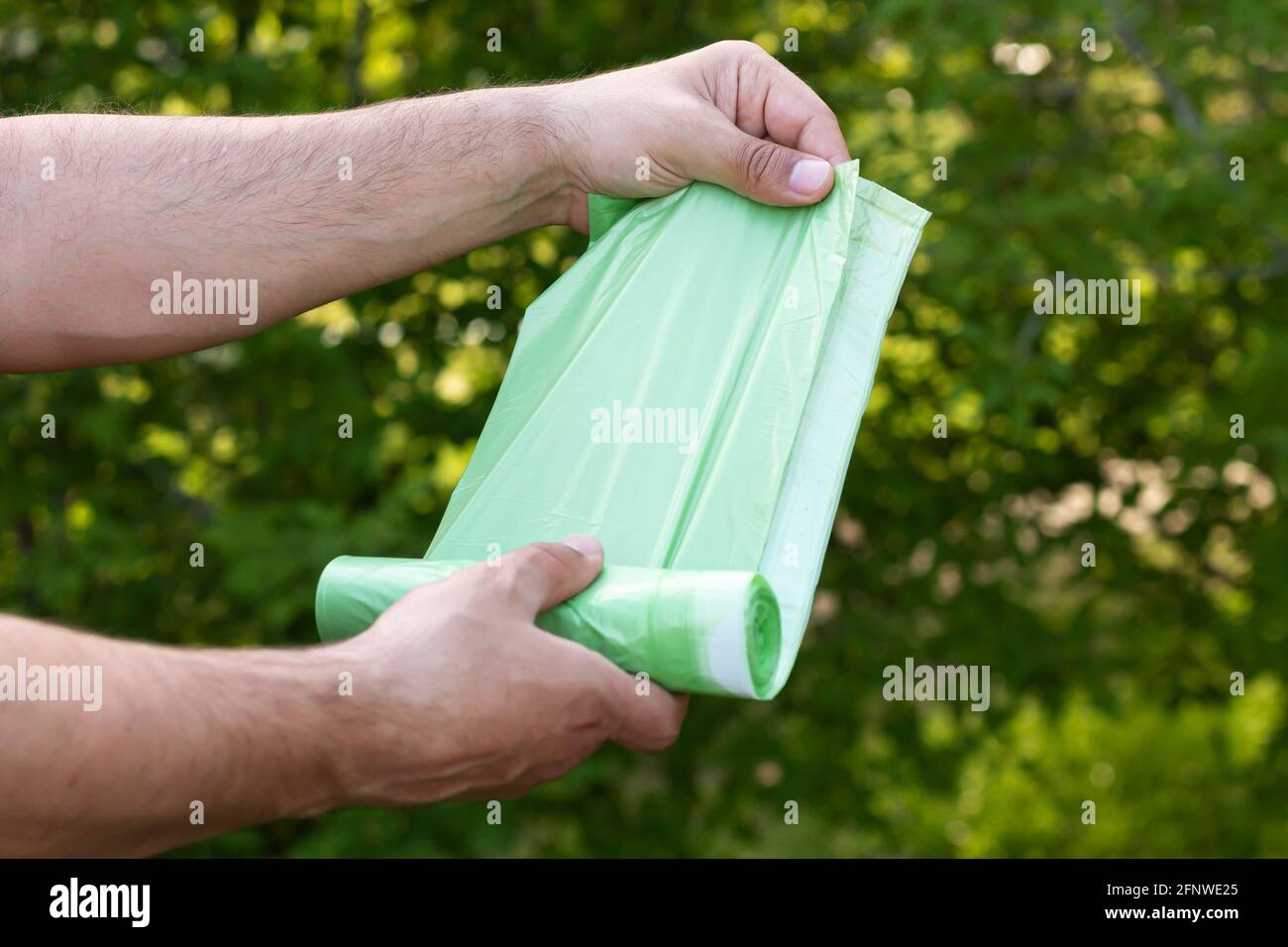 Uomo che tiene eco plastica spazzatura bio borsa in rotolo all'aperto, borsa per compostare rifiuti organici Foto Stock