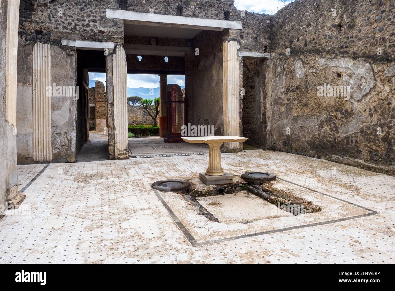 Atrio quadrato che ha un impianto centrale (serbatoio dell'acqua). Il pavimento dell'atrio è costituito da lava frantumata decorata con piccoli trucioli di marmo bianco. Casa del frutteto - Sito archeologico di Pompei, Italia Foto Stock