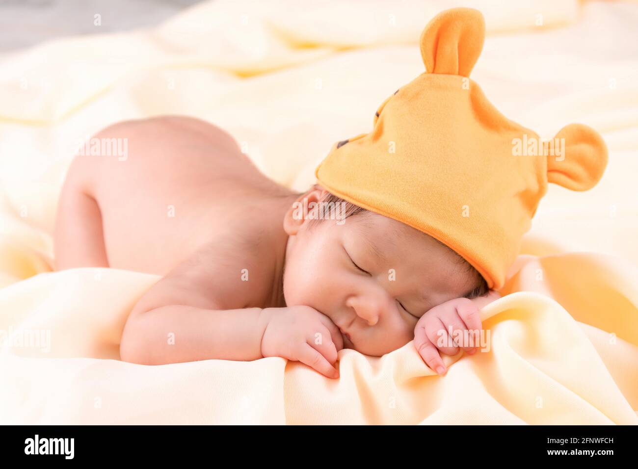 Ritratto di una bambina di un mese che dorme, neonato. Indossa un cappello  di lana arancione e dormi su una coperta di crema. Studio di ritratti di  concetto fas Foto stock -