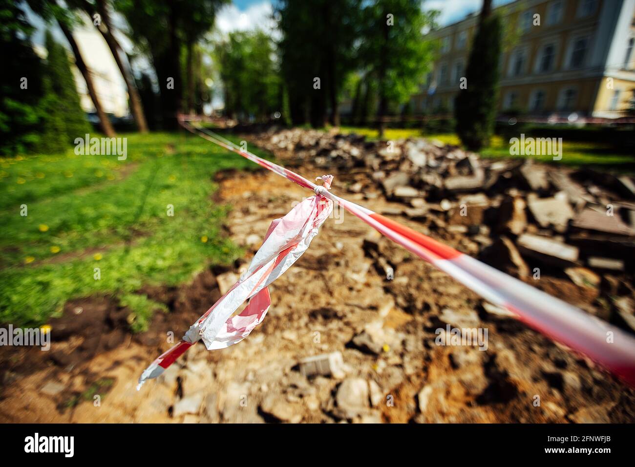 un nastro segnaletico impedisce il passaggio. nastro cordon attorno al luogo pericoloso. lavori di riparazione sul sito del guasto dell'asfalto dopo il disastro. cordon Foto Stock