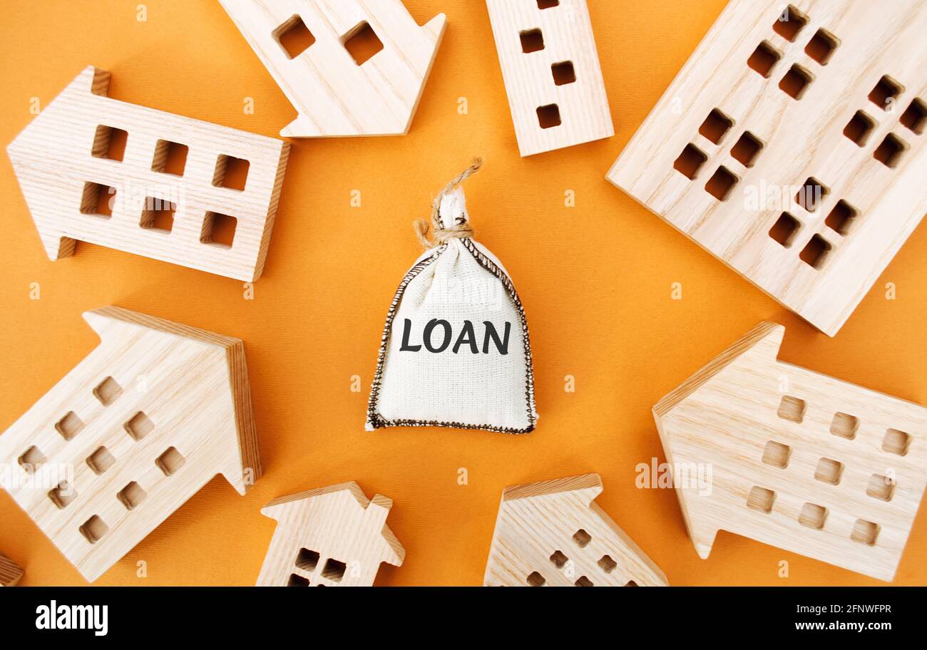 Borsa di denaro con la parola prestito e case di legno intorno. Il concetto di mutuo e prestiti immobiliari. Acquista un appartamento su credito. Leasing. AFF Foto Stock
