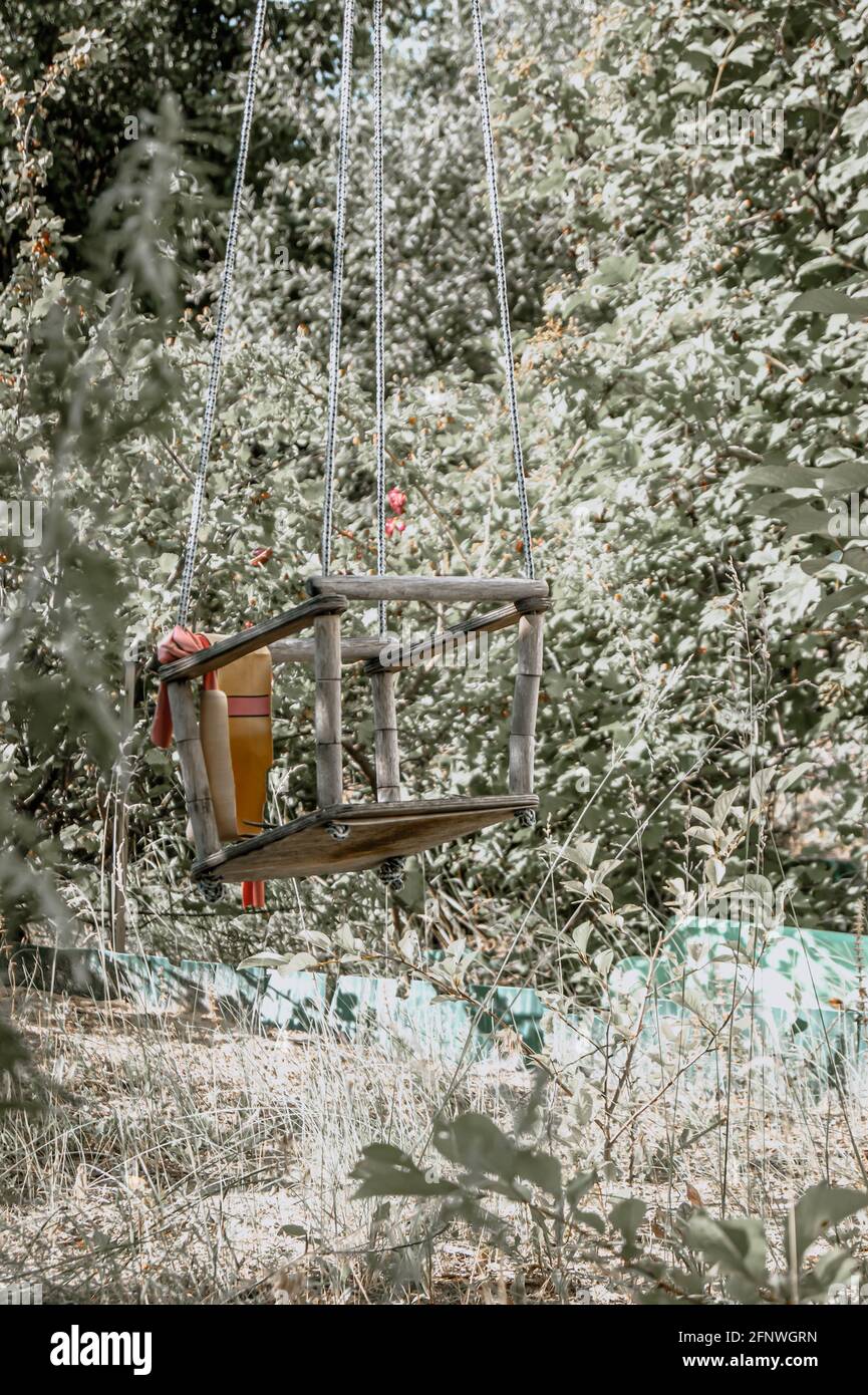 Un'oscillazione sopravfatta e abbandonata regolata nel mezzo della foresta. Un sacco di erba. La natura assume il controllo. Sensazioni strane. Foto Stock