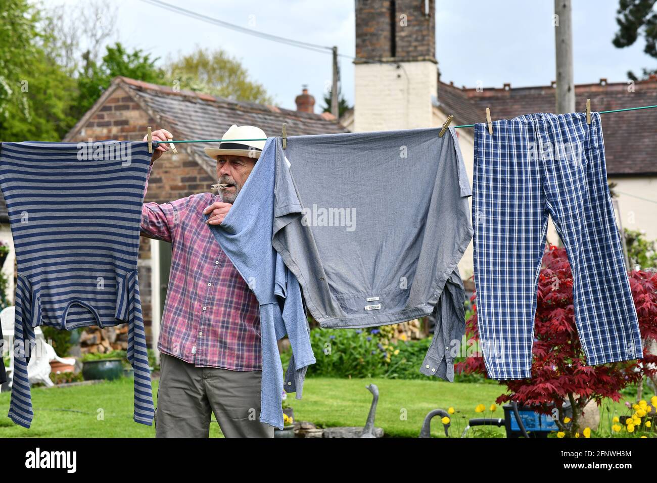 Uomo appeso lavaggio sulla linea di vestiti con i pioli nel giardino Gran Bretagna, UK. Addomesticato maschio che asciuga all'esterno casa chores lavoro uomini Foto Stock