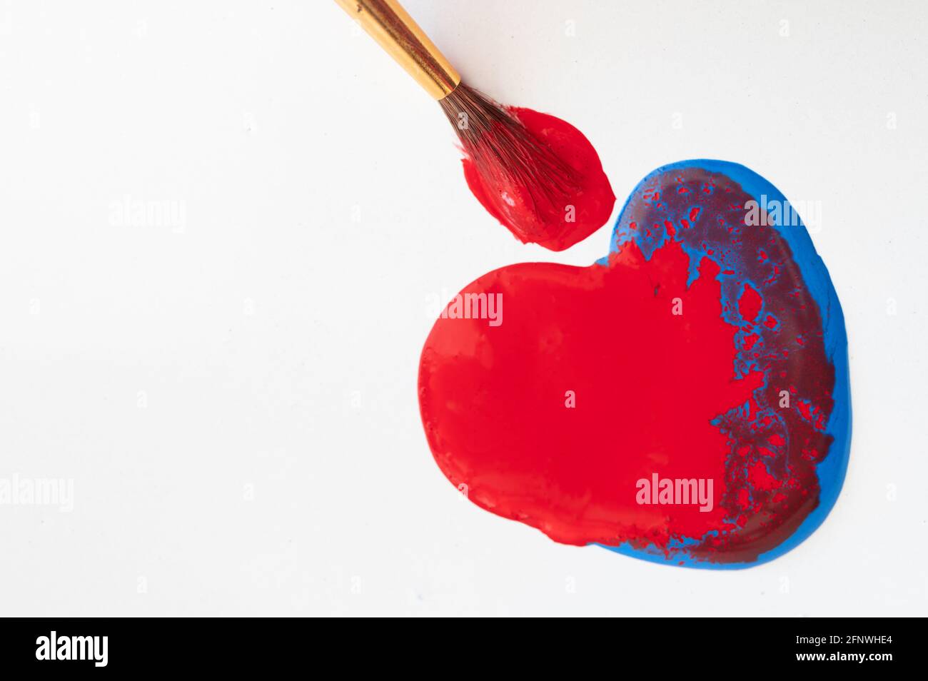 Vernice rossa e blu a forma di cuore con pennello Foto Stock