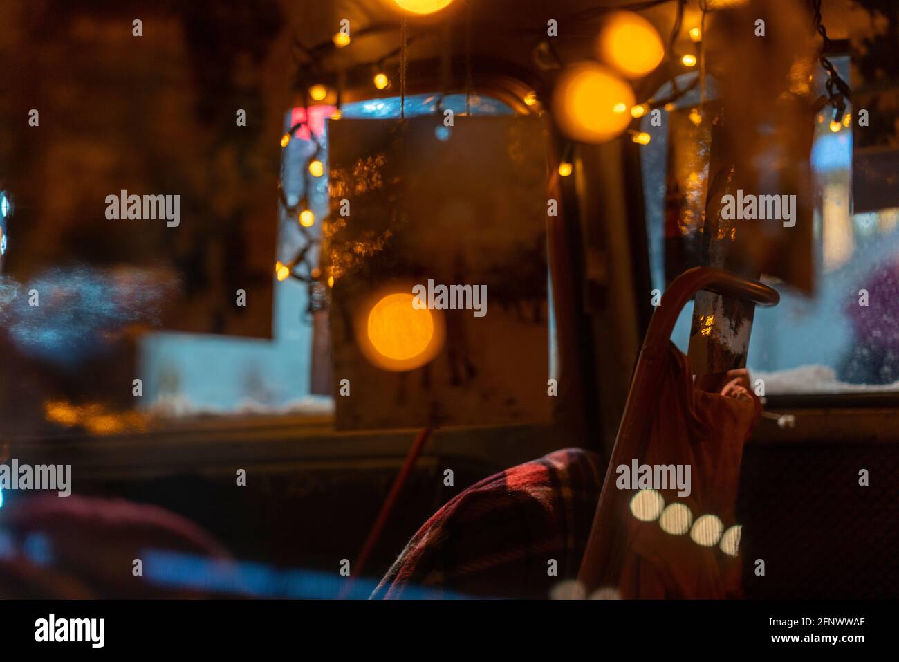 Vista del finestrino laterale posteriore di un'auto d'epoca rossa innevata con luci e decorazioni festive del nuovo anno Foto Stock