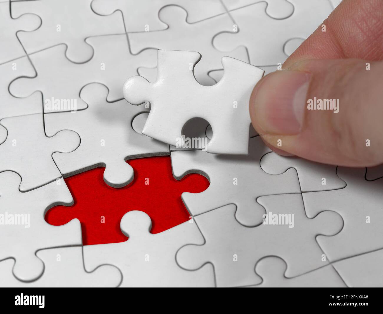 Closeup una mano maschio che tiene la soluzione puzzle jigsaw al problema mancante pezzo. Concetto metafora concettuale immaginare. Foto Stock