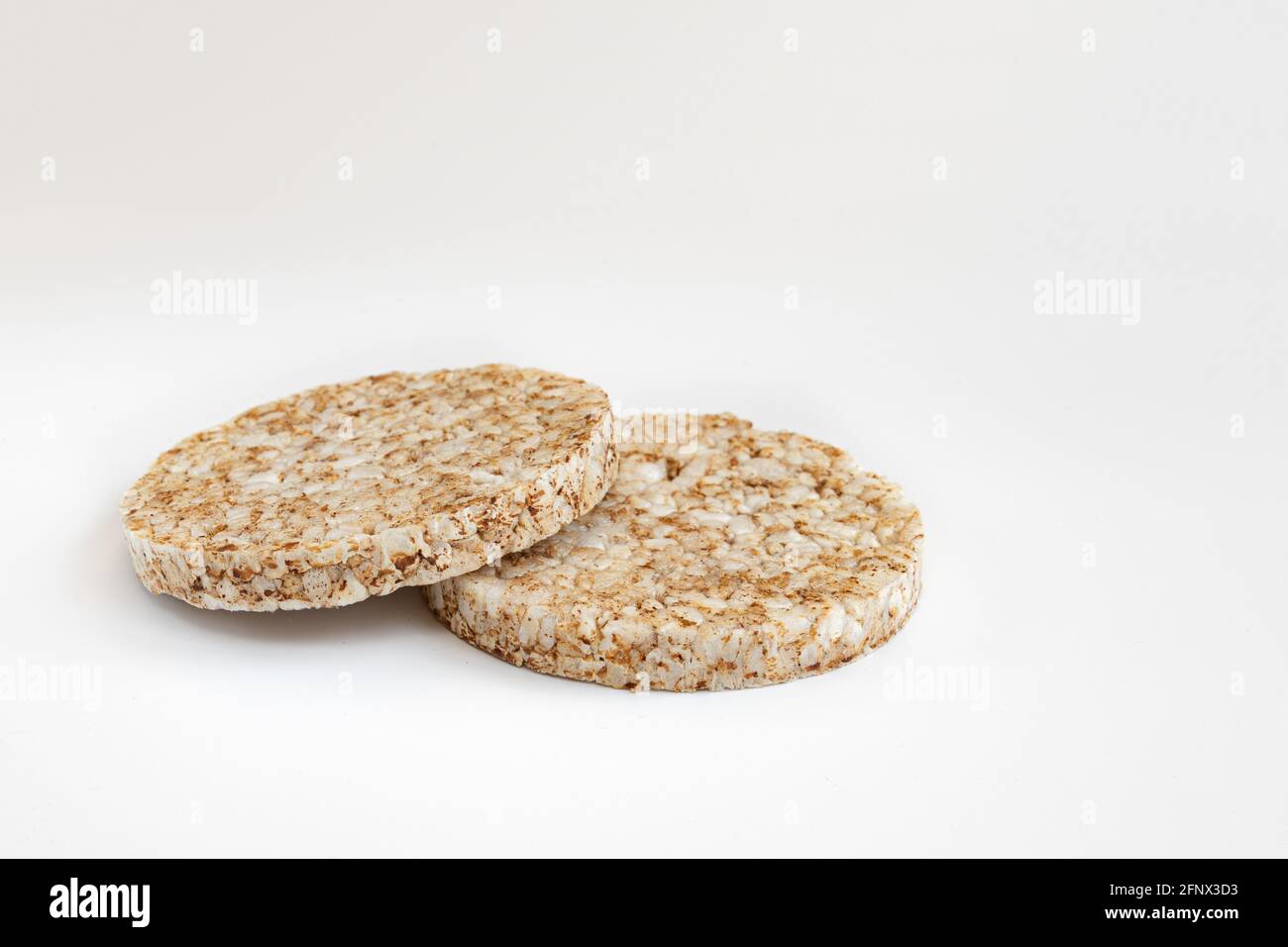 torte di riso croccanti su sfondo bianco, due frittelle di grano intero soffiato e spazio vuoto per il testo isolato, primo piano Foto Stock