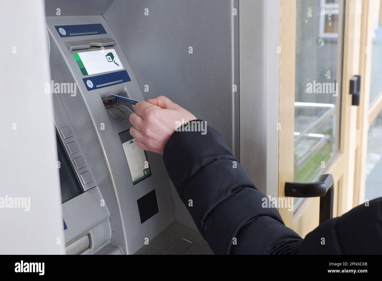 La mano di un uomo inserisce una carta di credito in un bancomat. Foto Stock