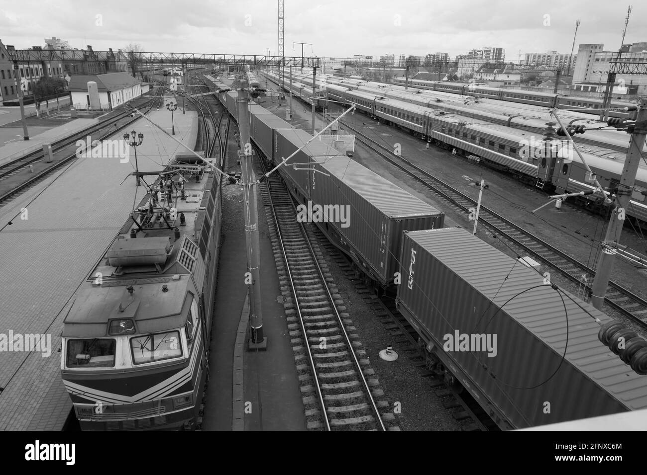 Treno per passeggeri parcheggiato nella vista dall'alto della stazione ferroviaria. Locomotiva e treno merci. Immagine in bianco e nero. Foto Stock