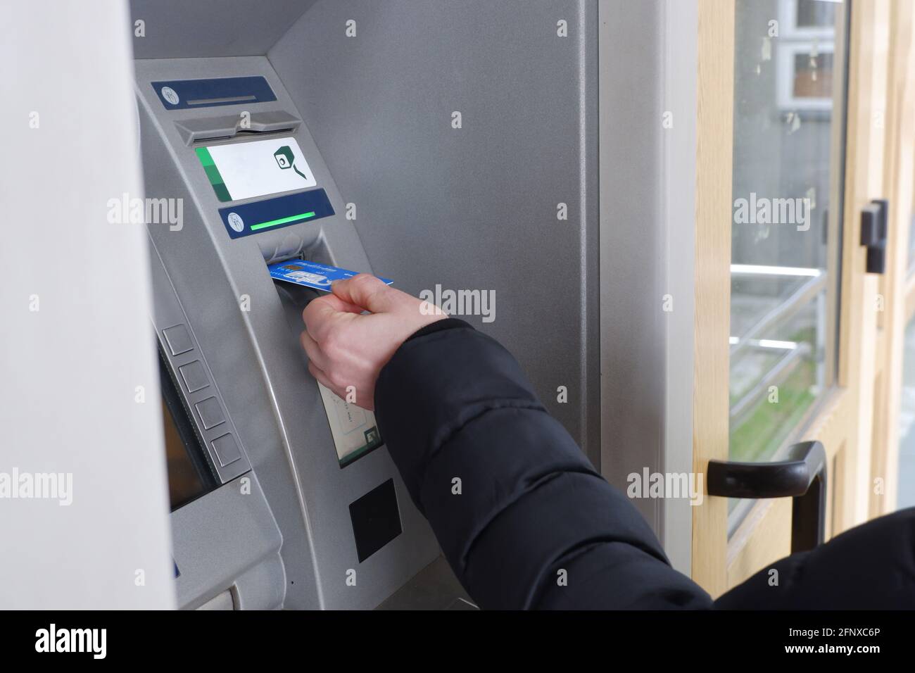 La mano di un uomo inserisce una carta di credito in un bancomat. Foto Stock