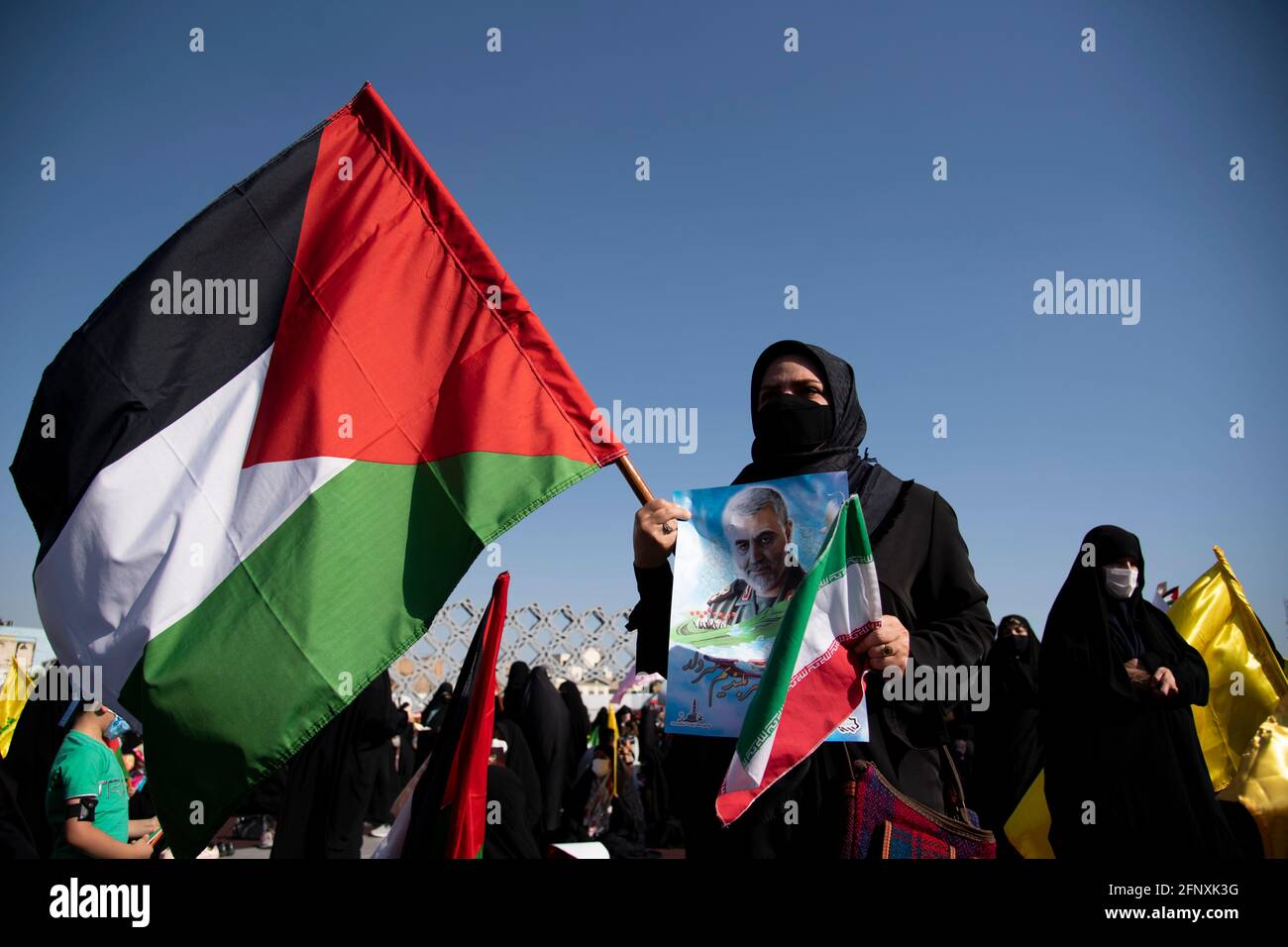 Teheran, Iran. 19 maggio 2021. Una donna iraniana detiene la bandiera palestinese e un ritratto dell'ex corpo della Guardia rivoluzionaria islamica iraniana (IRGC), il generale della Quds Force Qasem Soleimani, ucciso in un attacco di droni americani nell'aeroporto di Baghdad, Durante una riunione di protesta per condannare l'attacco missilistico israeliano a Gaza e l'uccisione di bambini, ad est di Teheran. (Foto di Sobhan Farajvan/Pacific Press) Credit: Pacific Press Media Production Corp./Alamy Live News Foto Stock